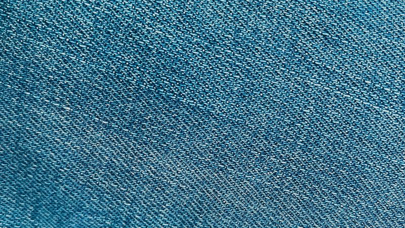 Detailed close-up of the textured surface of blue denim fabric.