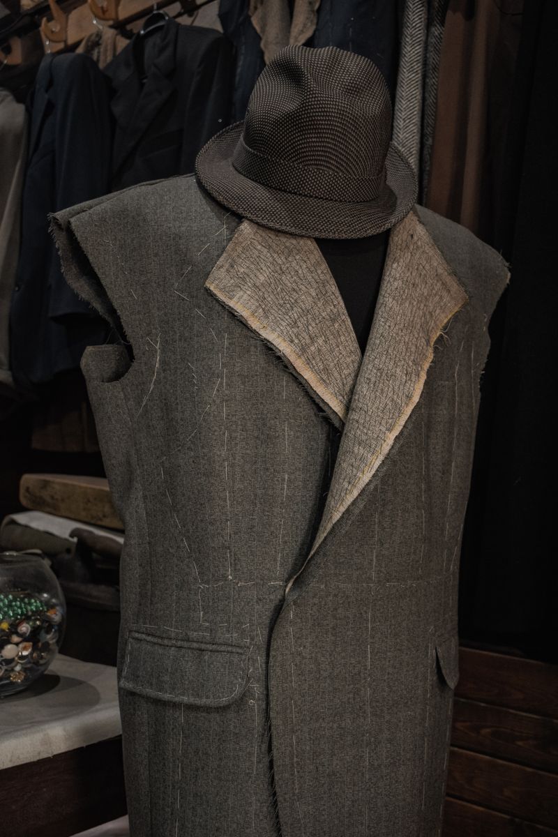 Tailor mannequin wearing an unfinished suit jacket in a workshop.