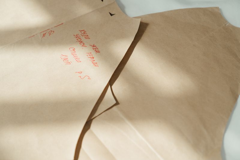 Close-up of sewing patterns on craft paper with handwritten notes in sunlight.