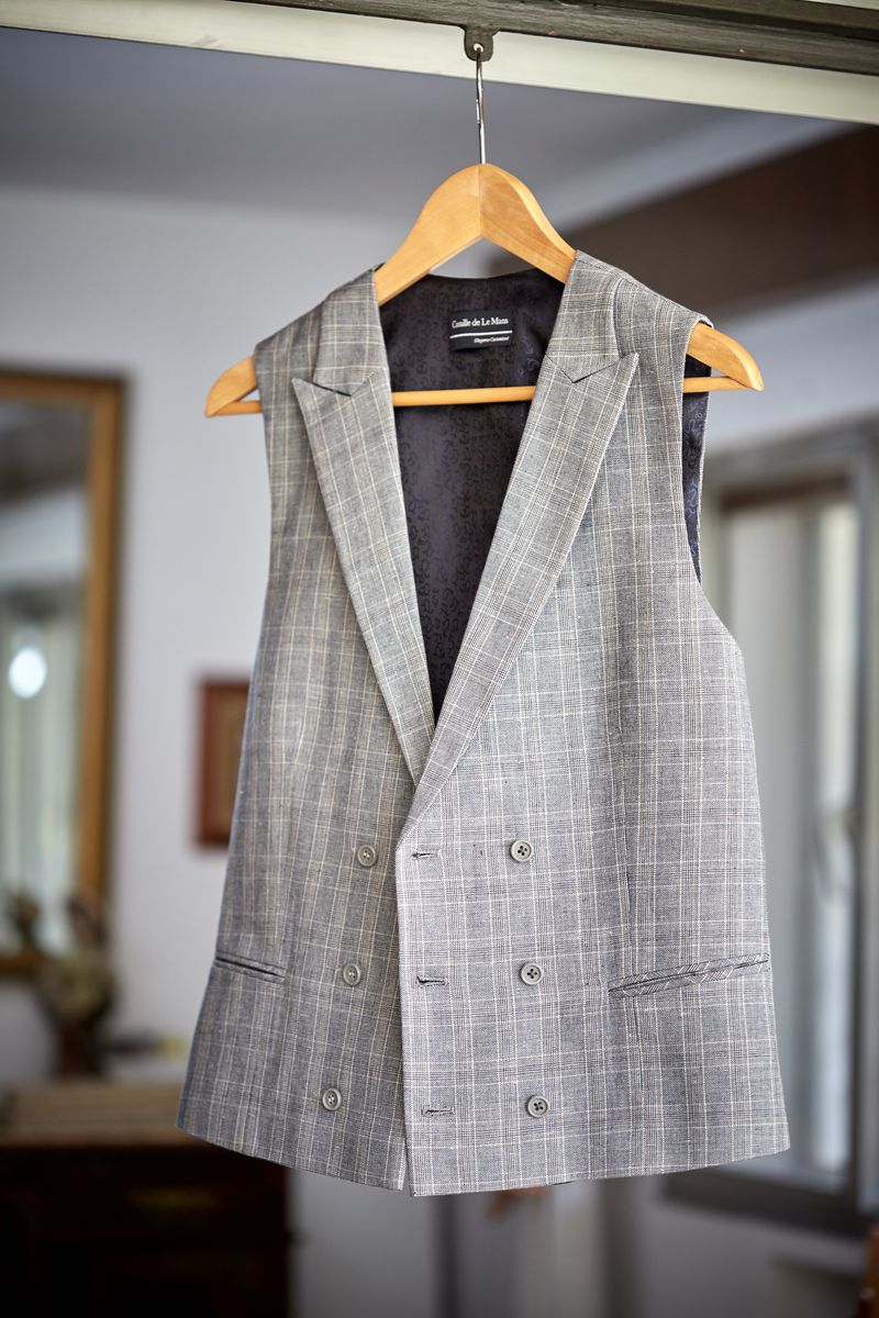 Stylish grey plaid vest hanging indoors with a classic wooden hanger.