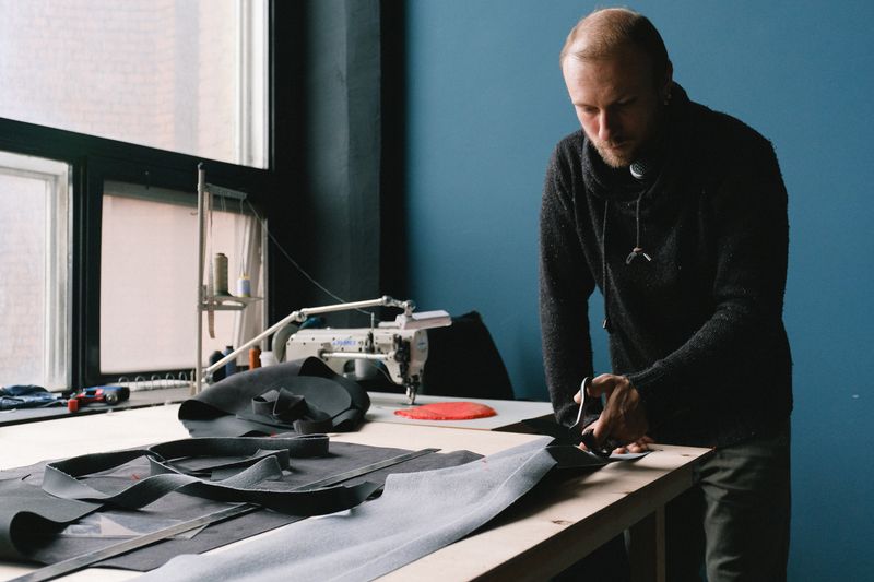 A tailor demonstrating precision cutting fabric in a workshop.