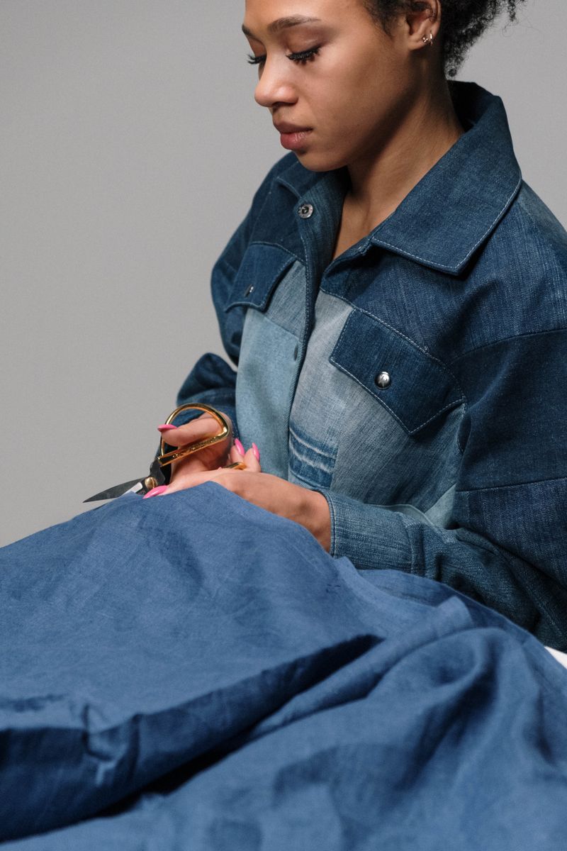 Skilled seamstress cutting blue fabric indoors.