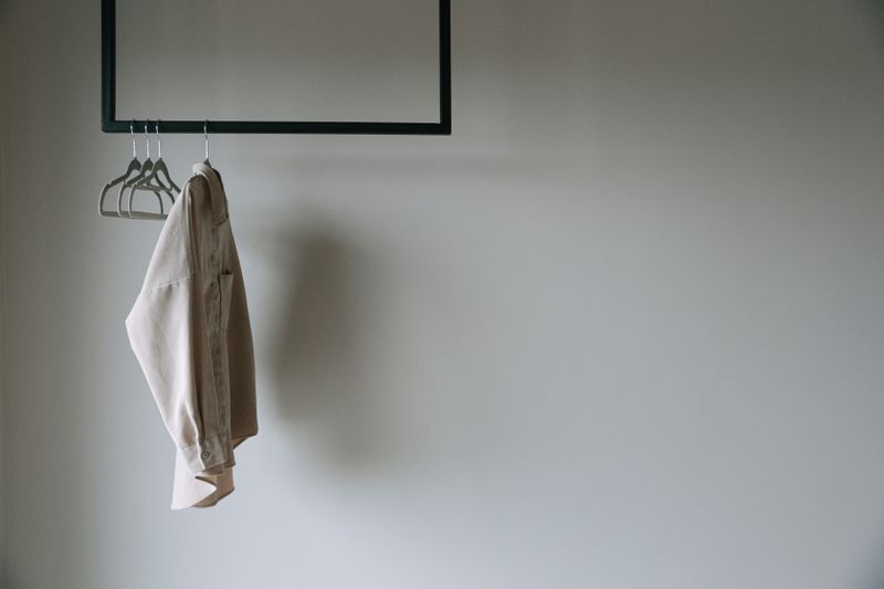 A beige blazer hangs on a minimalist metal rack.