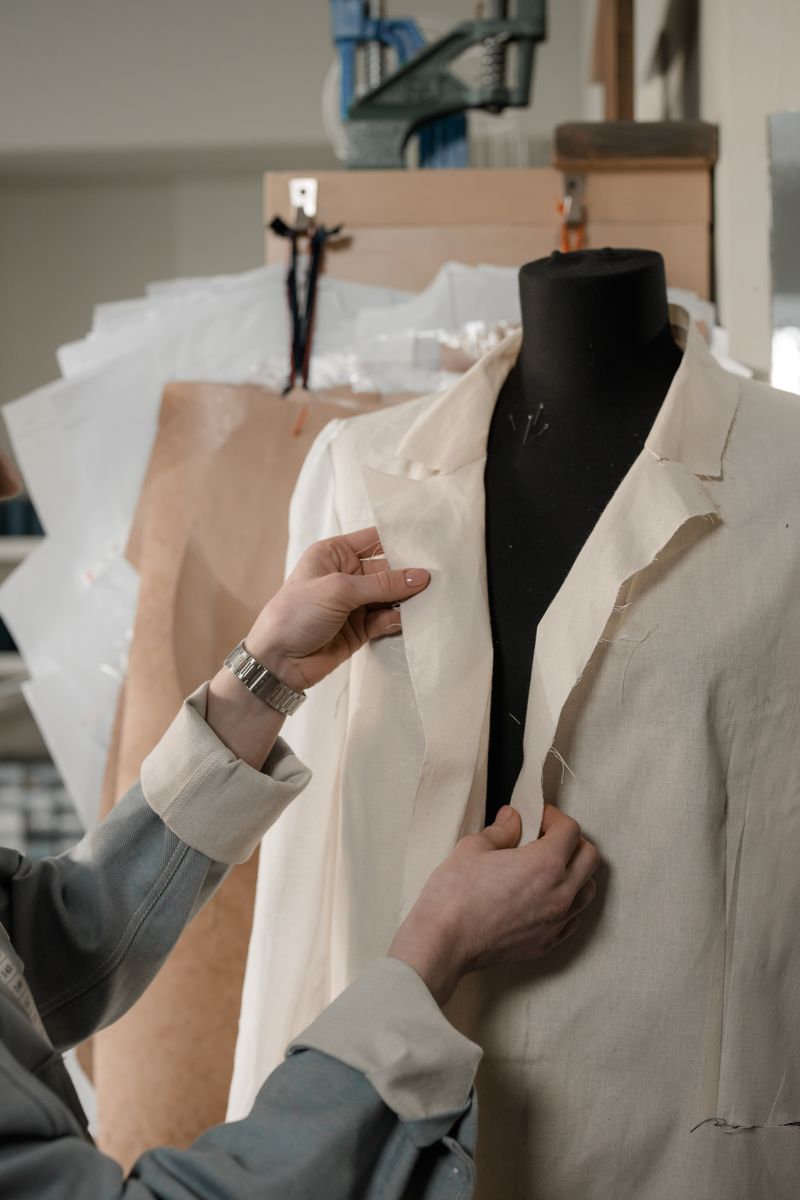 Tailor adjusting a jacket on a mannequin in a sewing studio.