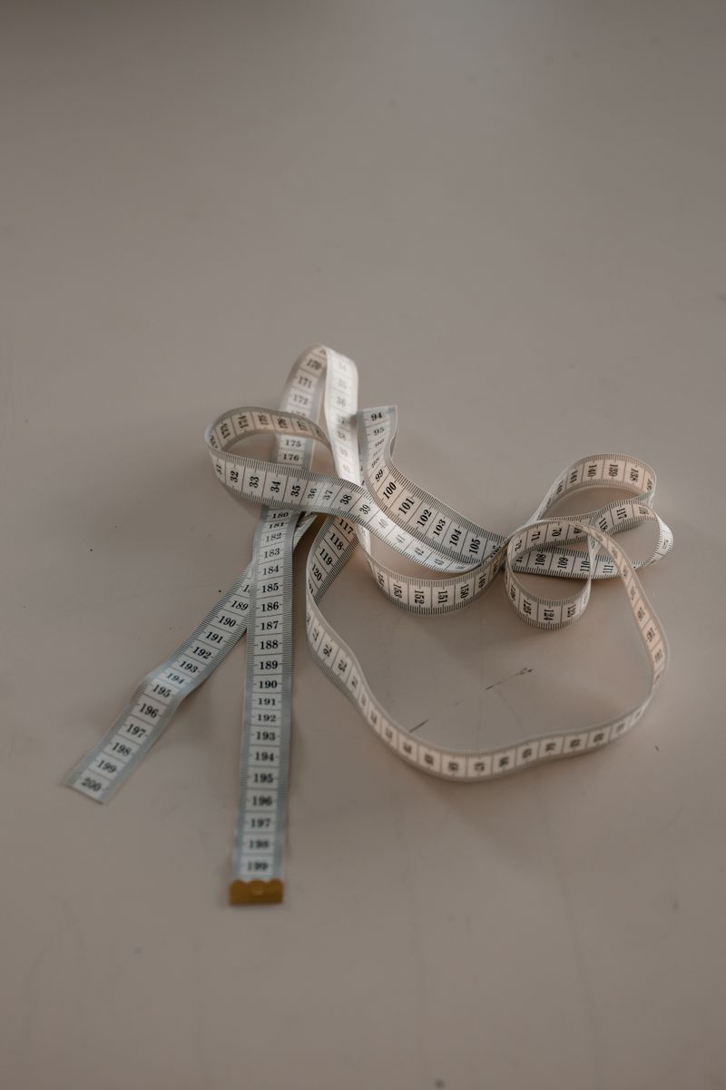 Close-up of a white measuring tape curled on a neutral background.