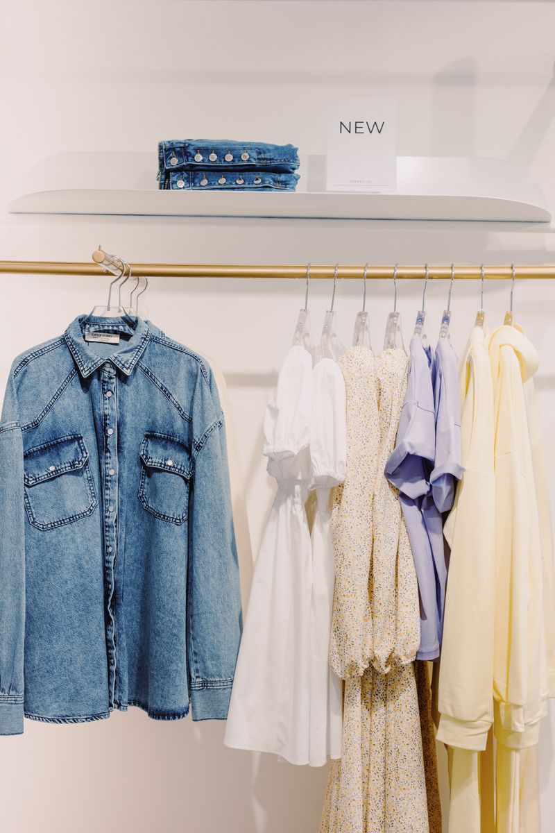 A neatly arranged assortment of clothing featuring a denim jacket in a boutique setting.