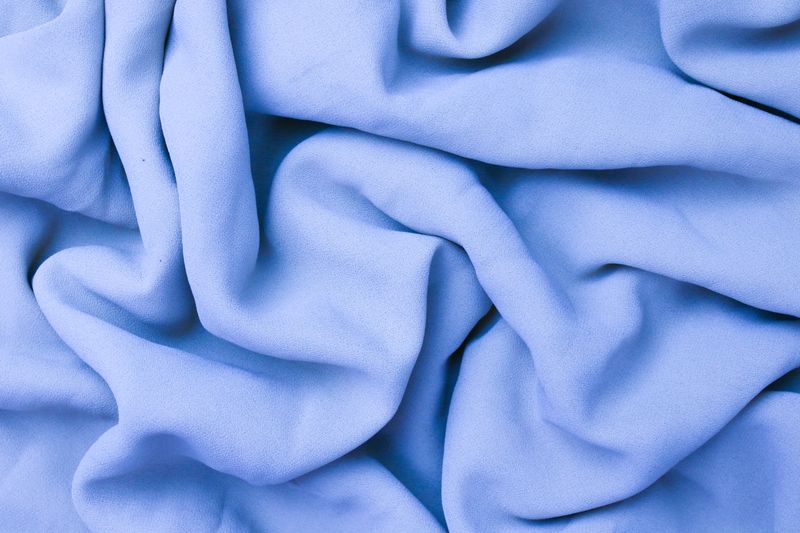 Close-up of soft blue fabric with wrinkled texture and smooth creases.